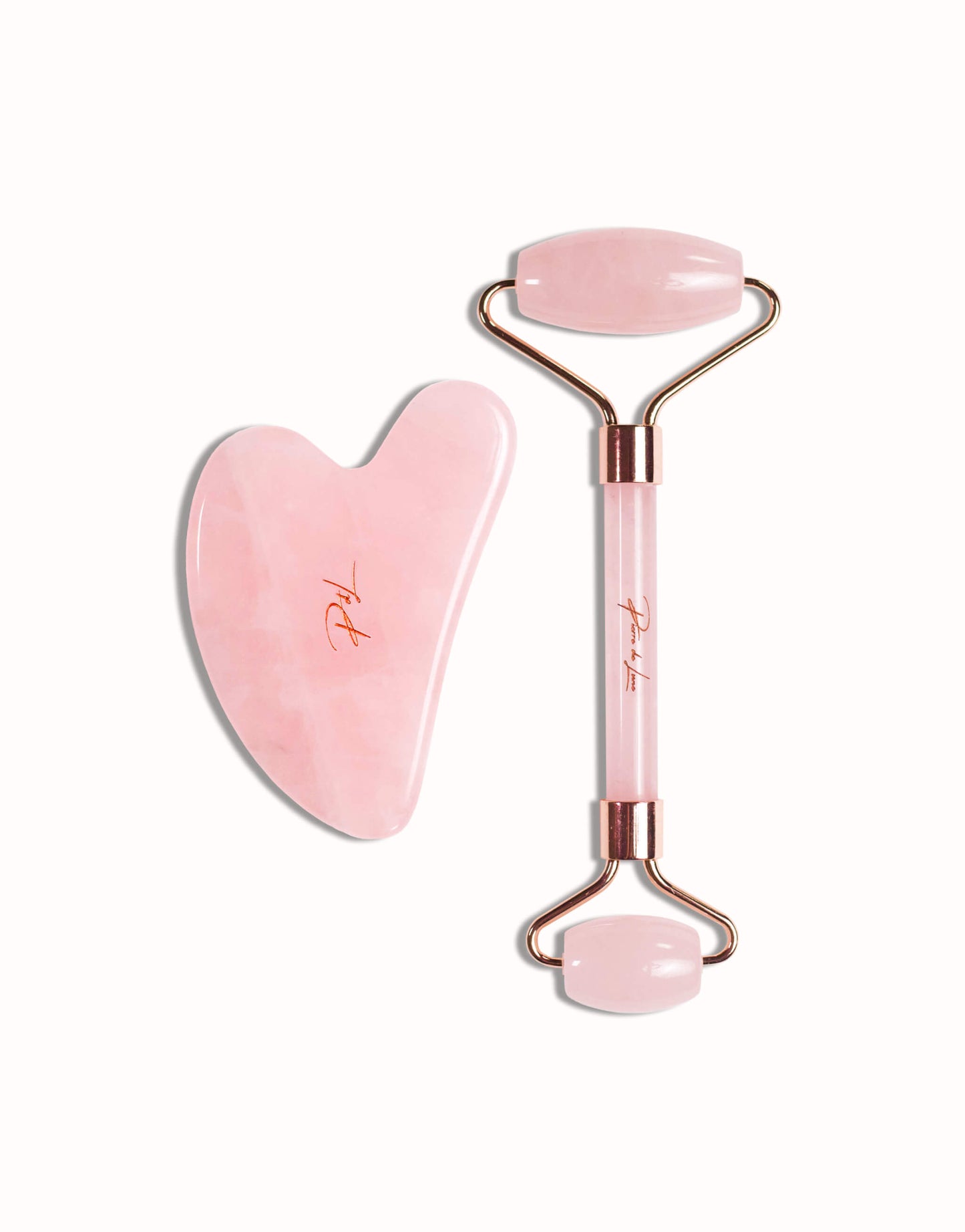 Gua sha et roller en quartz rose naturel, présentés sur un fond blanc, mettant en valeur leur qualité et leur finition élégante.