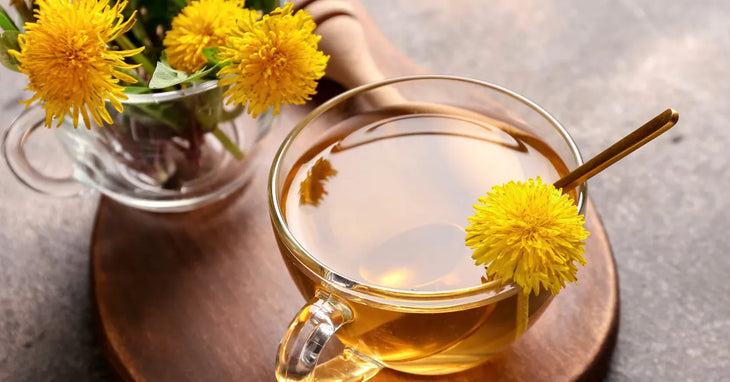 Tasse de tisane de pissenlit fraîchement infusée, posée sur un plateau en bois, accompagnée de fleurs de pissenlit fraîches – remède naturel pour le drainage lymphatique